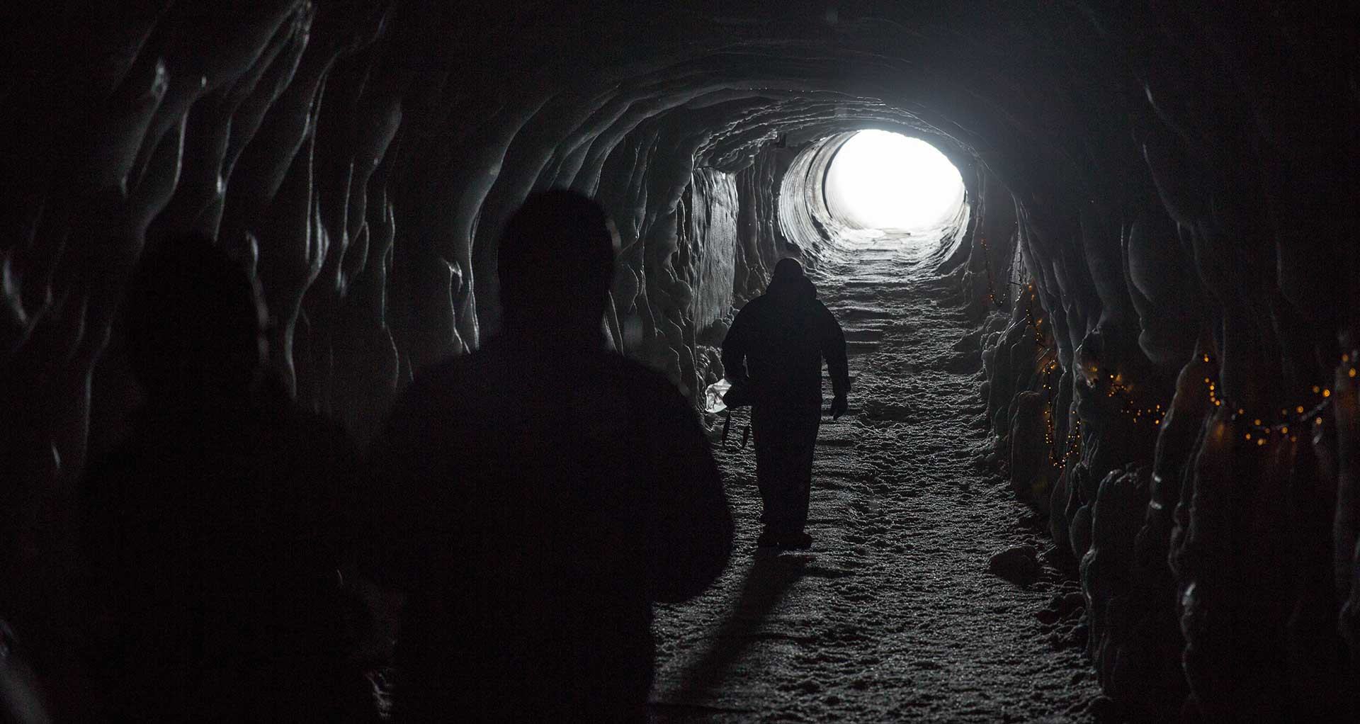 Men walking towards a light at the end of the tunnel.