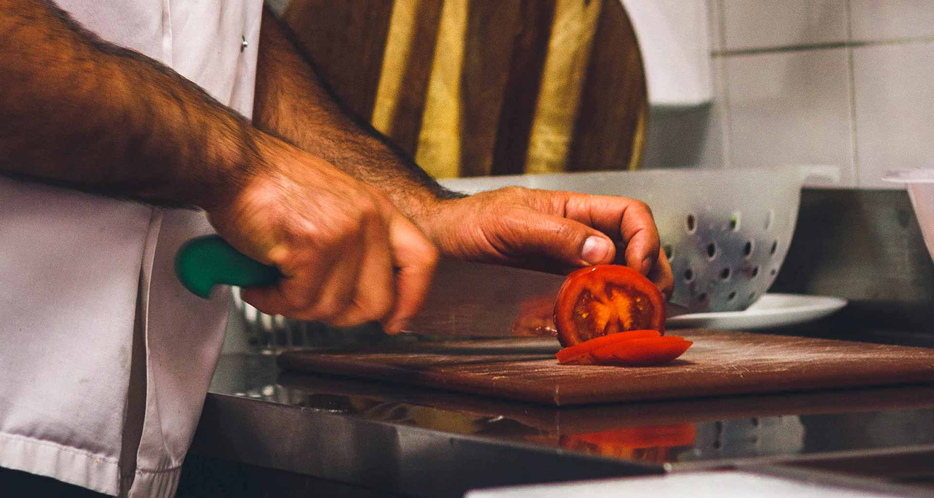 Chef slicing a tomoato.