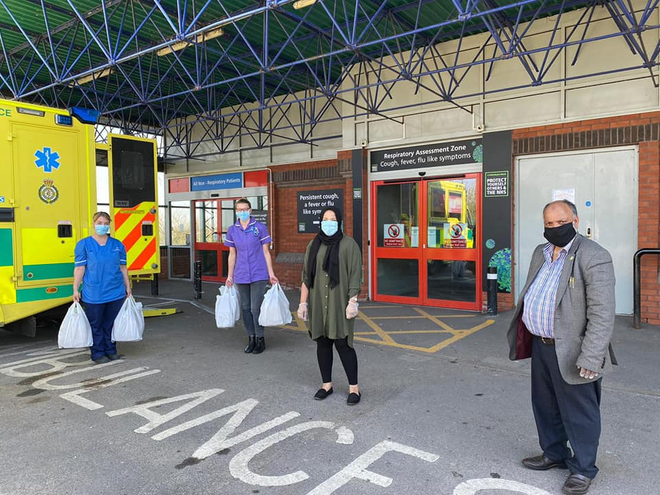 Two nurses and two people stood outside a hospital with food bags.